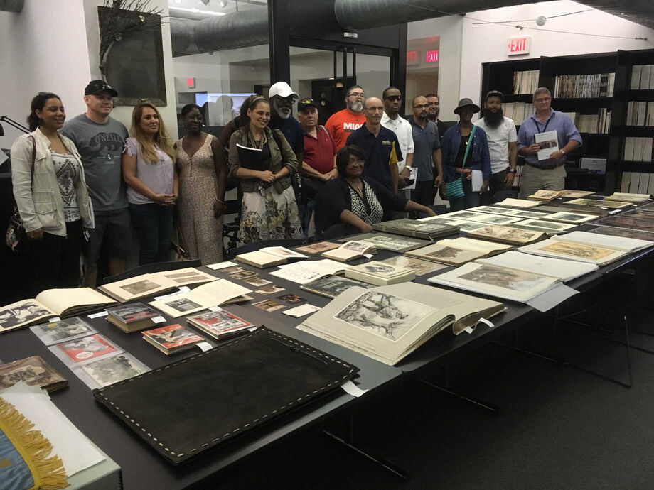 Reading and discussion group participants gather around documents during their  visit to the Wolfsonian-FIU. Image courtesy of  Florida International University.