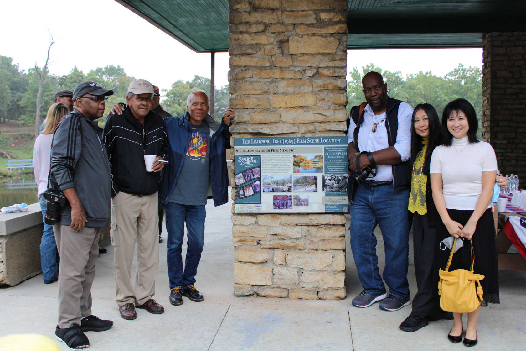 *The Learning Tree* Film Scene and Sign Trail was unveiled at a ribbon cutting ceremony during Fort Scott's annual Gordon Parks Celebration. In this image, special guests gather around an interpretive sign, from left to right: Duane "Michael" Cheers (associate professor of photojournalism, San Jose State University); David Parks (filmmaker, author, and son of Gordon Parks); Kyle Johnson (actor, "Newt" in *The Learning Tree* and 2021 Choice of Weapons honoree); Eli Reed (photographer and journalist, 2021 Choice of Weapons honoree); Sandra Chen Weinstein (documentary and fine arts photographer); and Aileen Wang (associate curator, Beach Museum of Art at Kansas State University). Image courtesy of the Gordon Parks Museum.
