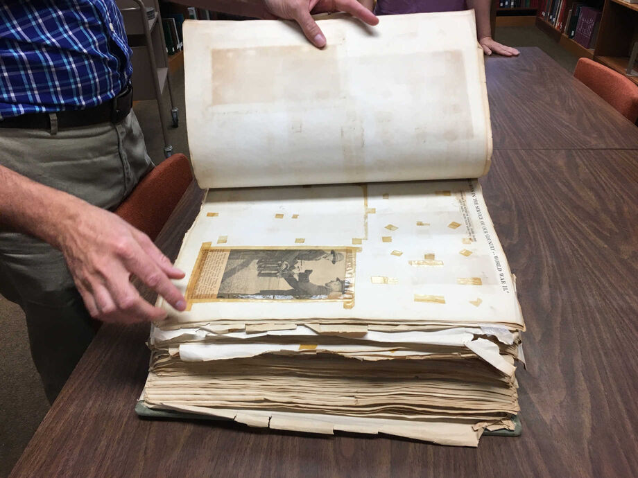 Conservators examine a scrapbook during a preservation assessment at an academic library. Image courtesy of LYRASIS.