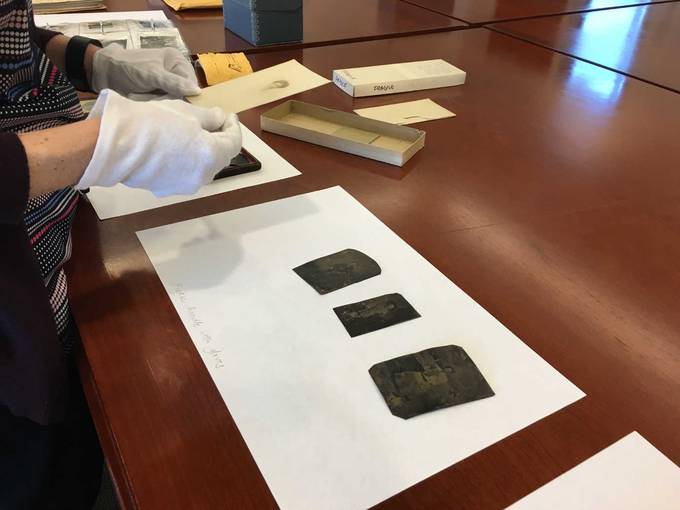 A conservator examines tintypes during a preservation assessment at a community college. Image courtesy of LYRASIS.
